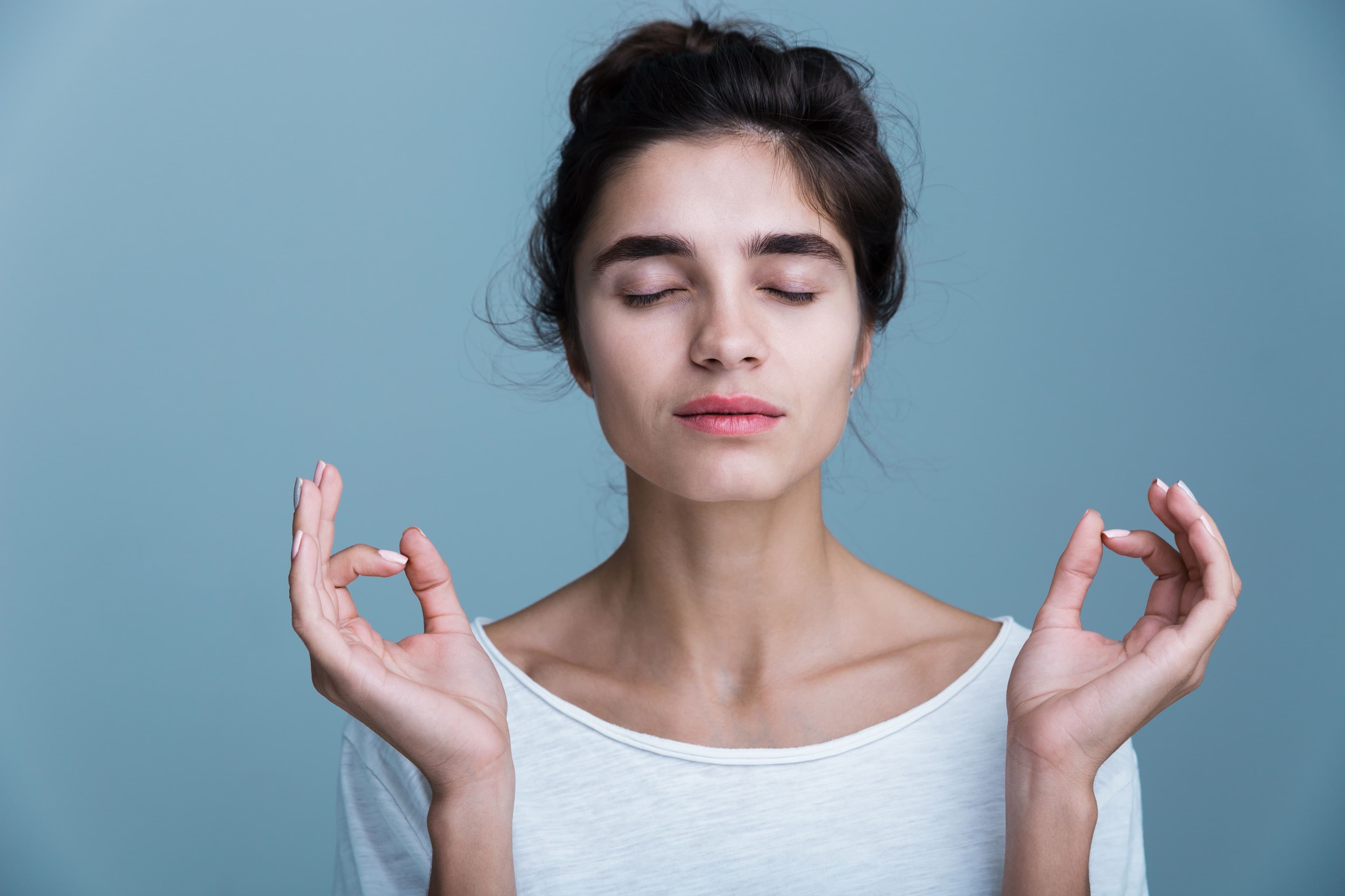 A relaxed woman practicing meditation with closed eyes, promoting cortisol reduction, stress relief, and hormonal balance for overall well-being.