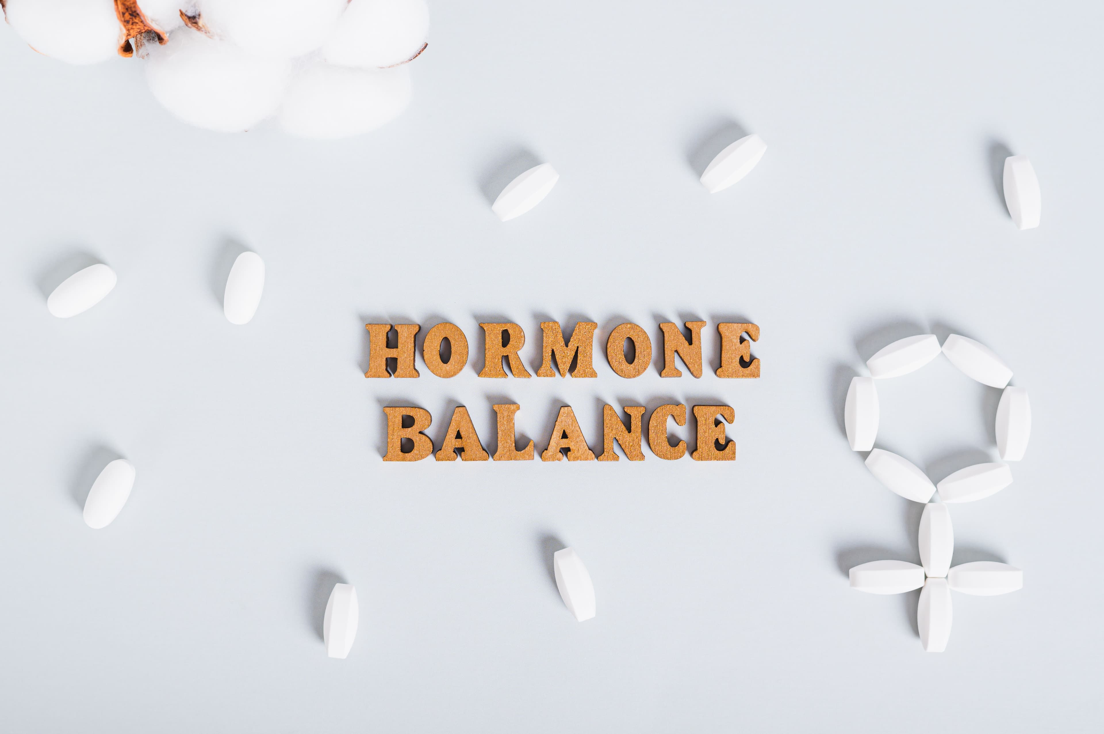 Conceptual image representing hormonal balance with the word 'HORMONE BALANCE' surrounded by pills on a light blue background, emphasizing estrogen and hormonal health.