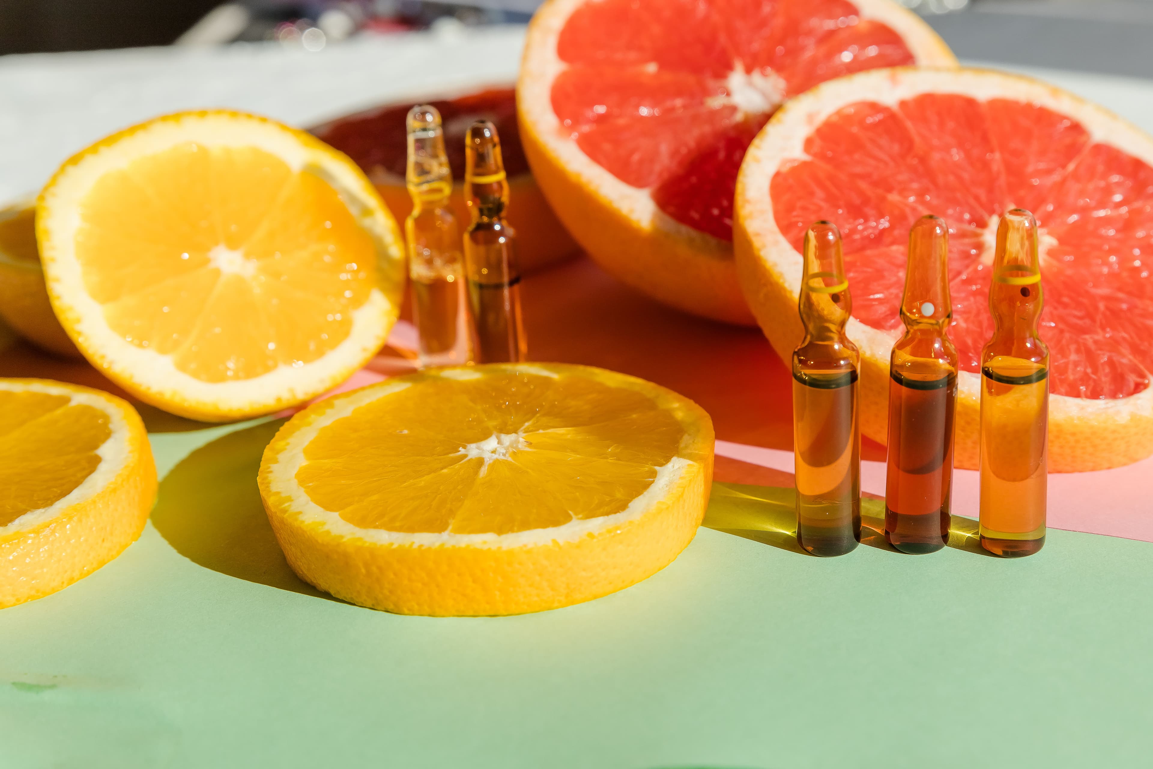 Fresh orange and grapefruit slices alongside vitamin ampoules, representing a rich source of amino acid-supporting vitamins for overall health and wellness.