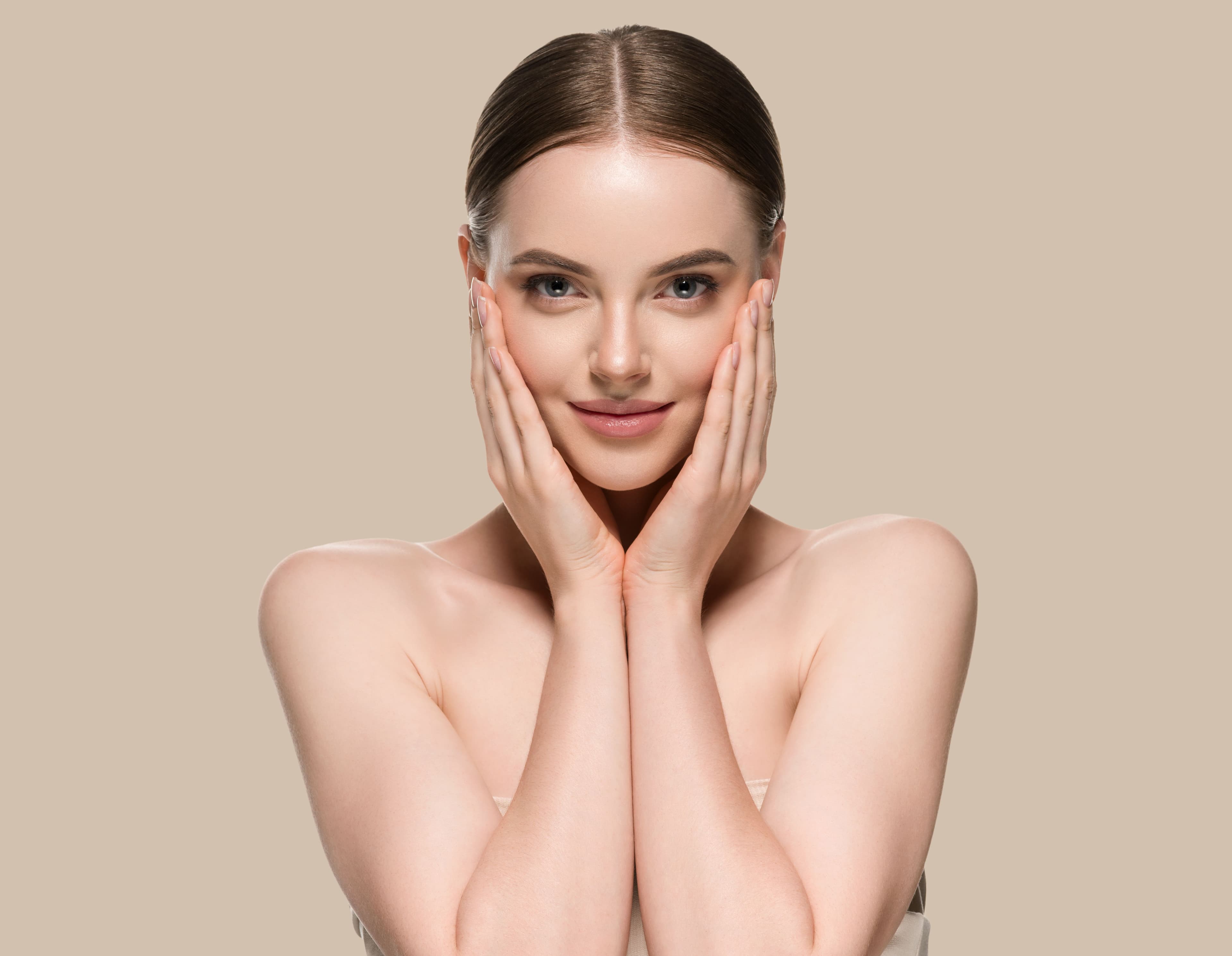 Portrait of a woman with glowing skin holding her face in her hands, symbolizing the role of minerals like magnesium and zinc in promoting healthy skin